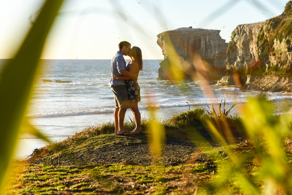 coupe kissing behind the grass at Muriwai beach