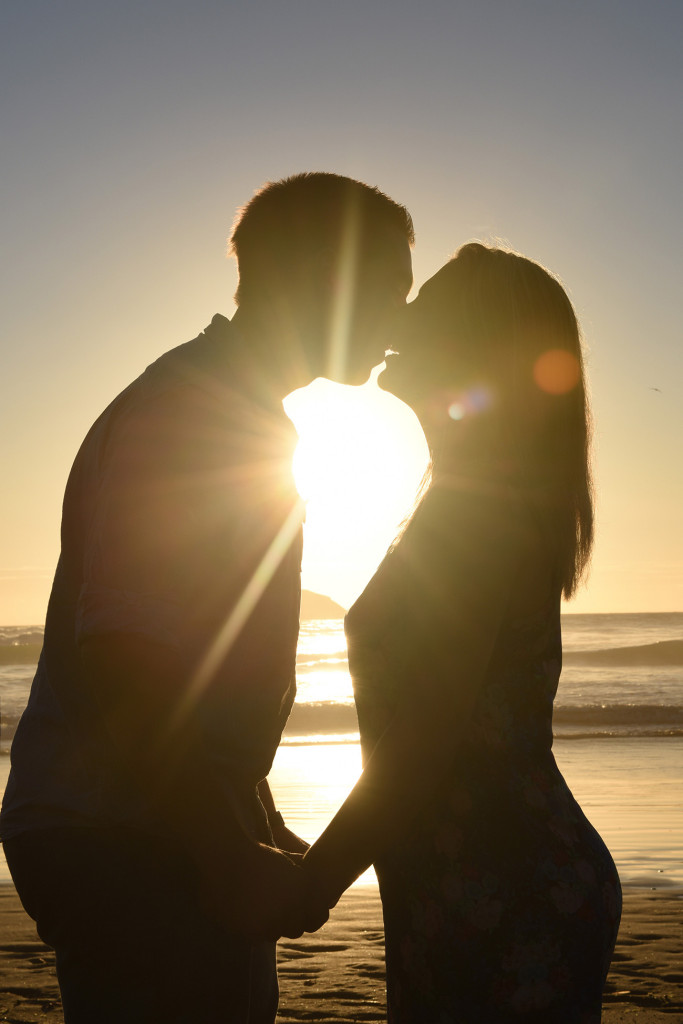 couple kissing silhouette with sun and sea behind