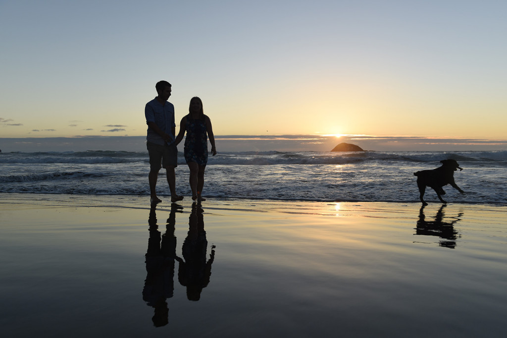 couple and their reflection on the wet black sand beach