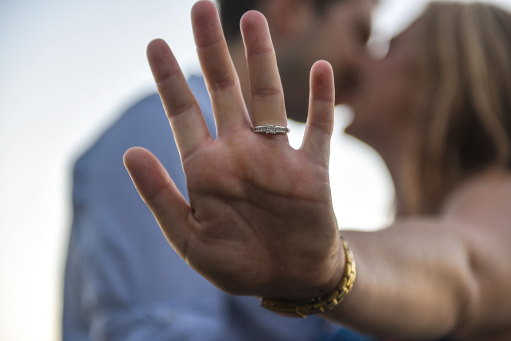 Ring on hand and blurred couple kissing
