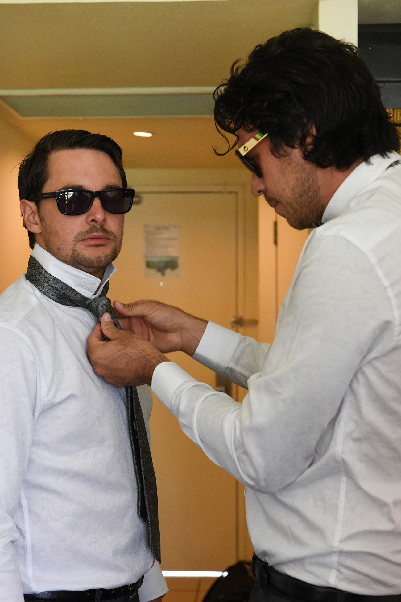 One of the groomsmen helping the groom to put his tie