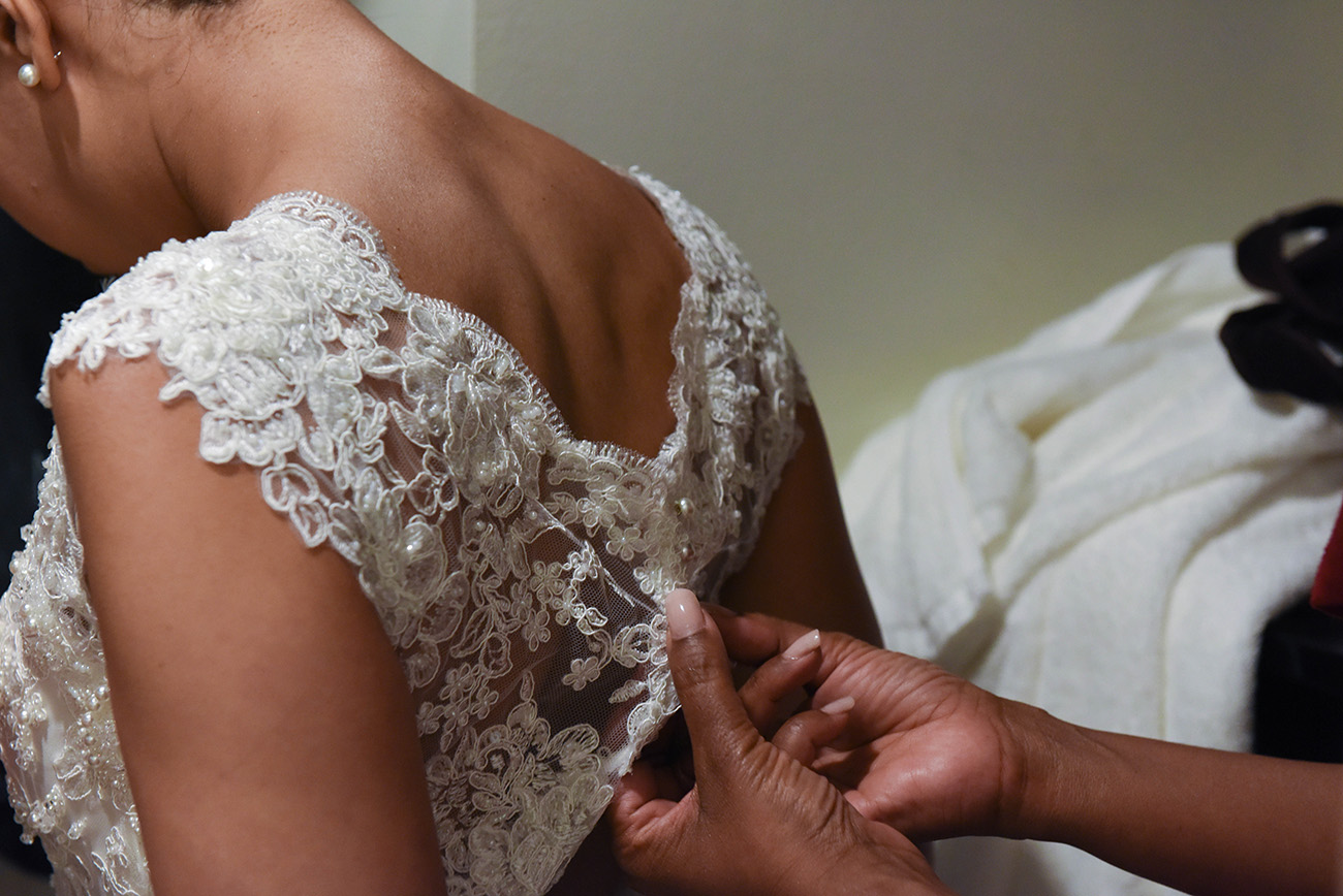 One of the bridesmaids tying the wedding dress on the bride's back