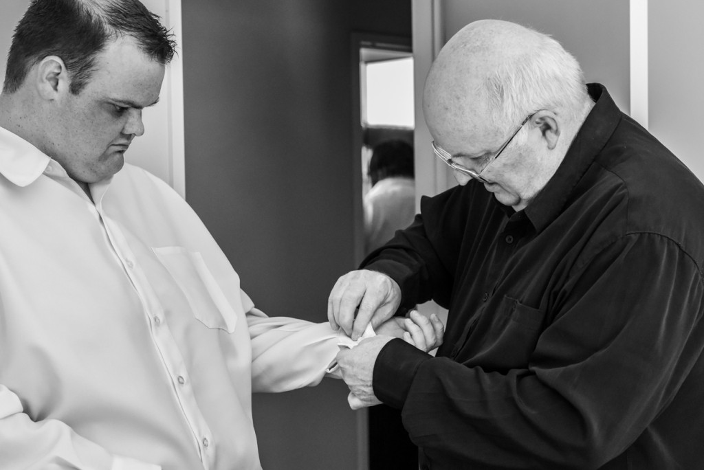 The groom's father helps the groom tying his cuffs