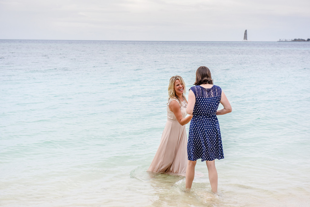 The bride laughs with a friend at the sea at her family Beach Wedding on Malolo Island, Plantation Island Resort, Fiji Wedding Photographer