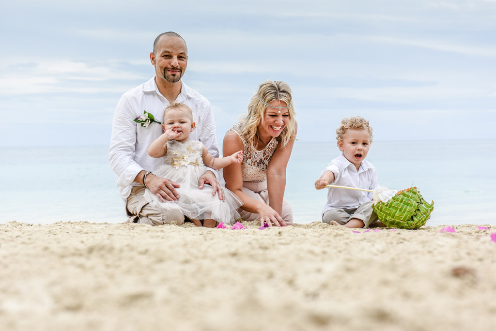 The family sits in the sand at their family Beach Wedding on Malolo Island, Plantation Island Resort, Fiji Wedding Photographer