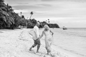 The couple runs hand-in-hand on the shores of the sea at their family Beach Wedding on Malolo Island, Plantation Island Resort, Fiji Wedding Photographer