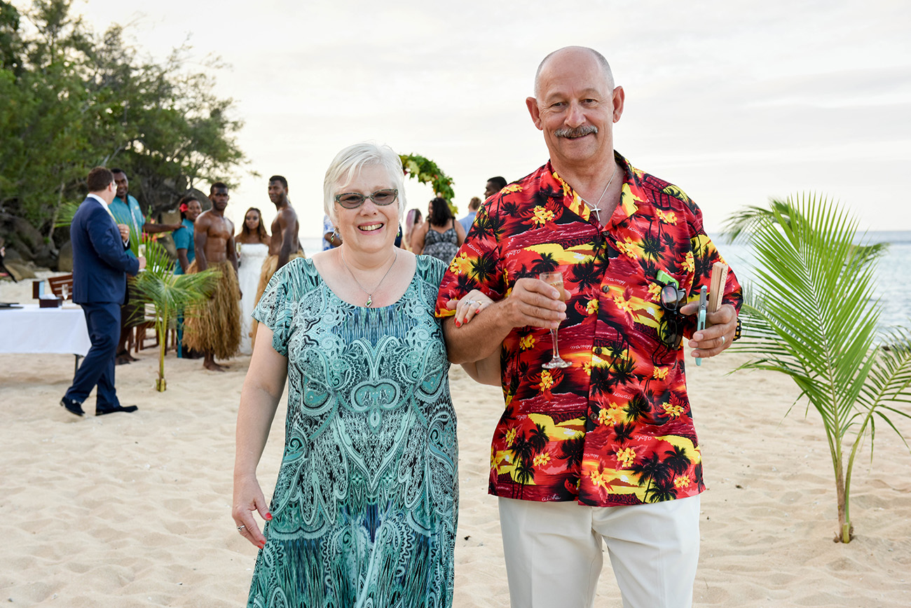 Father and mother of the groom walking along the beach at Paradise Cove Island Resort in the Yasawas, Fiji by Anais Photography