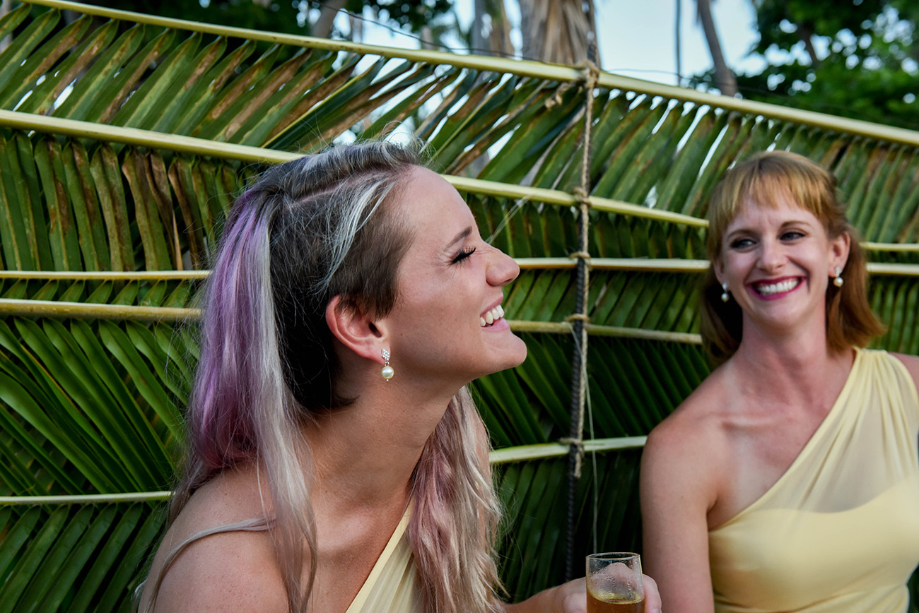The bridesmaid are laughing with palm leafs in the background at Paradise Cove island resort in the Yasawas in Fiji photographed by Anais Photography