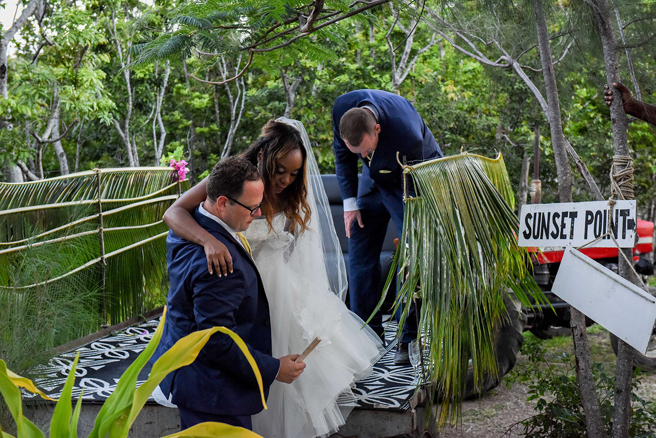 The groom is helping his wife to get down the tractor at Paradise Cove island resort in the Yasawas in Fiji photographed by Anais Photography