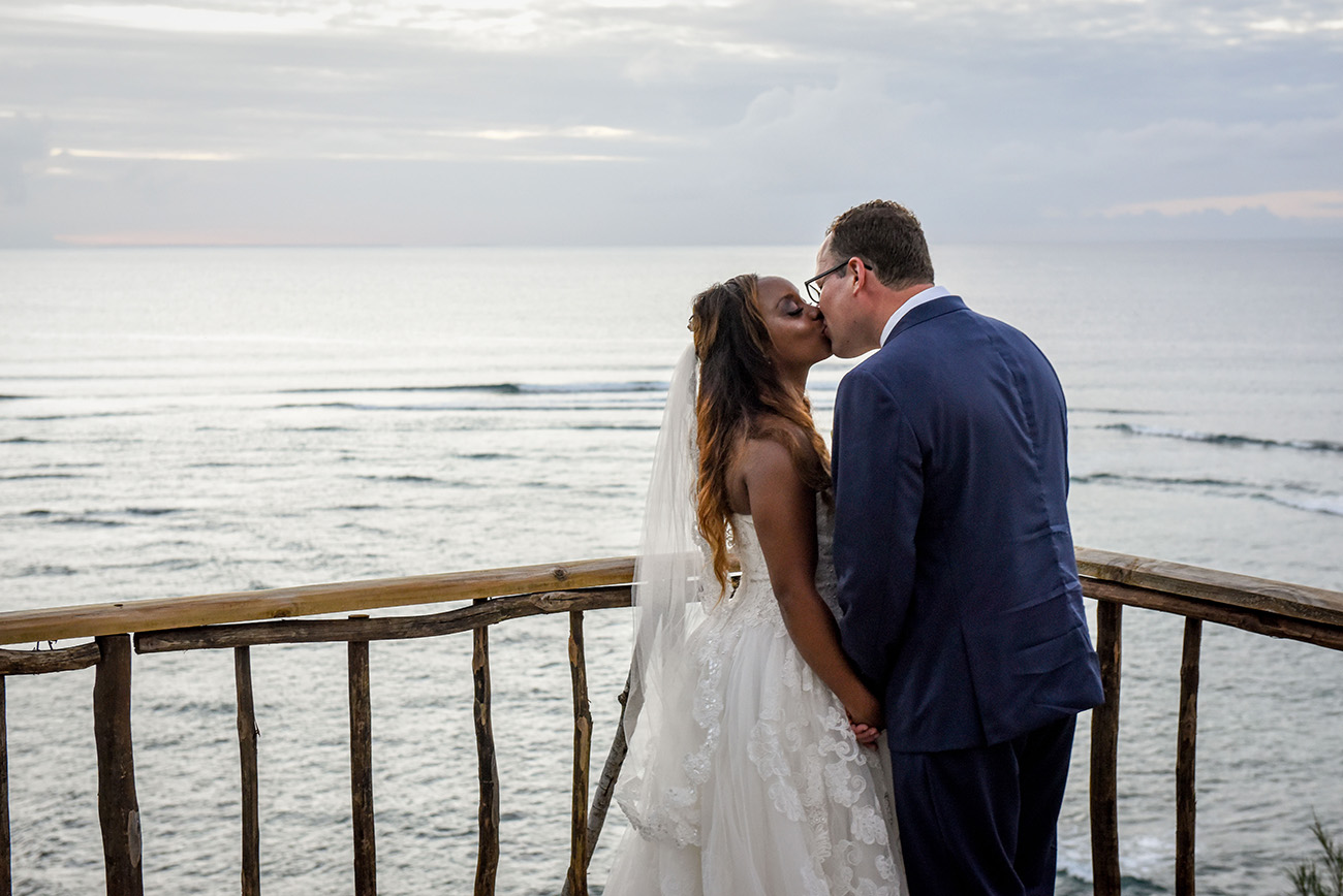 The bride and the groom are kissing overseeing the ocean while the sunset at Paradise Cove island resort in the Yasawas in Fiji photographed by Anais Photography