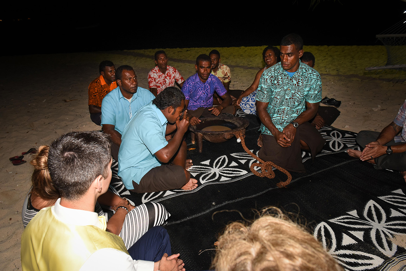 The kava ceremony between the local Fijians and the foreigner guests who are drinking together on the beach at Paradise Cove island resort in the Yasawas in Fiji photographed by Anais Photography