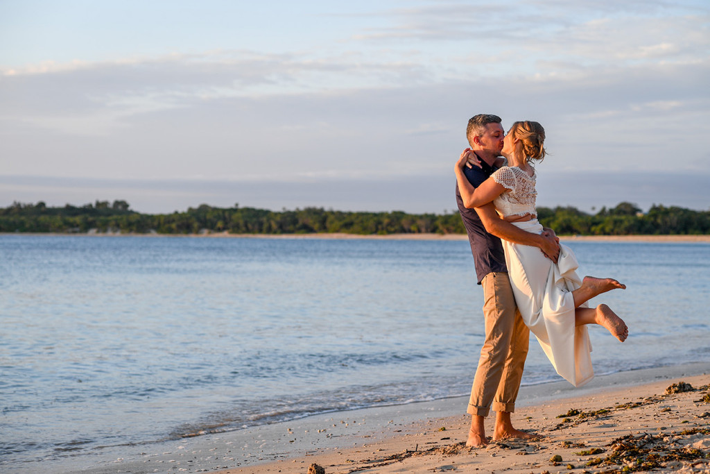 Groom lifts bride on Coral Coast beach
