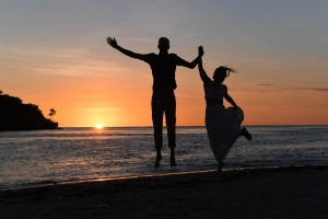 Silhouette of eloped couple jumping in sunset in Fiji Yatule Resort Beach