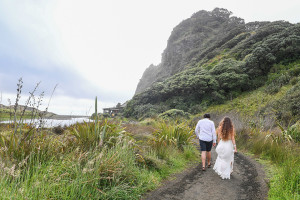 Eloping couple walk down the beach of Karekare NZ