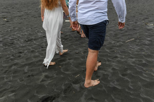 Bride and groom walk down the black sand beaches of Karekare New Zealand