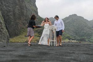Celebrant and couple in elopement wedding ceremony on the Black sand beach of Karekare NZ