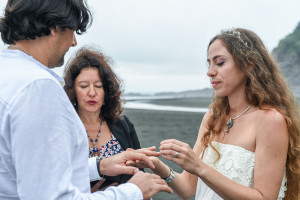 Groom wears ring at Karekare Beach Auckland New Zealand