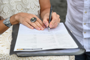 Bride signs marriage certificate at elopement wedding Karekare Beach Auckland NZ