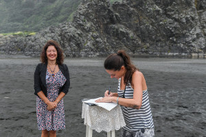 Photographer Anais Chaine signs marriage certificate as witness in elopement wedding at Karekare Beach Auckland NZ