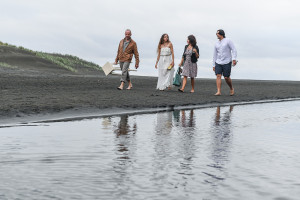 Newly married couple, celebrant and witness walk on Black sand beaches of Karekare Auckland NZ