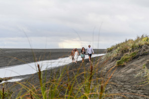 Newly married couple, celebrant and witness walk on Black sand beaches of Karekare Auckland NZ