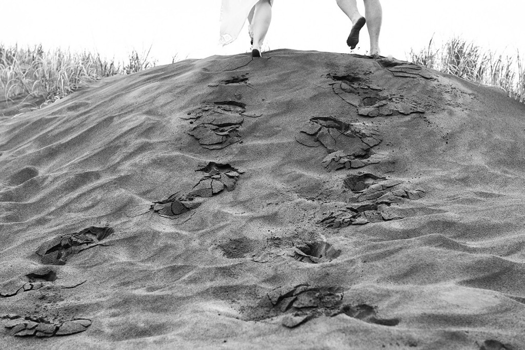 Newly eloped couple leave footsteps in black sand beach of Karekare Auckland NZ