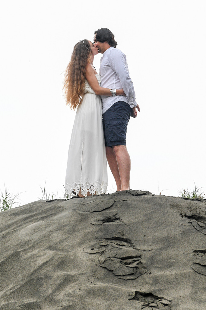 Eloped couple share a moment on a hill on black sand beach of Karekare Auckland NZ