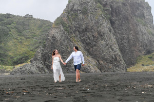 The newly married couple stroll together on the beach of Karekare NZ Auckland
