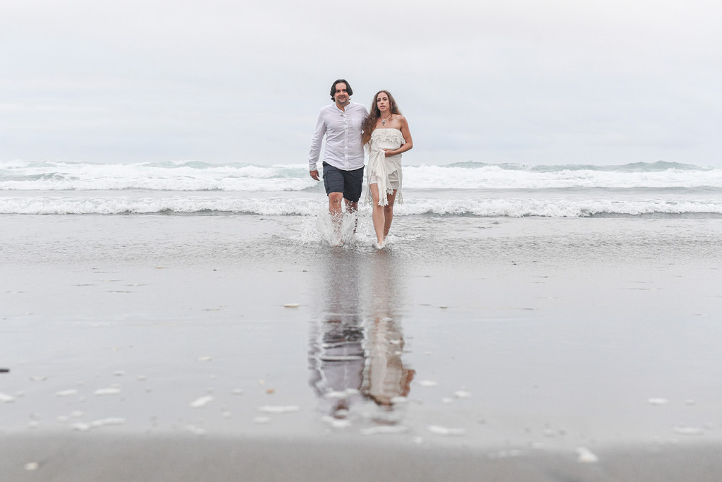 Bride and groom walk from the sea at Karekare Beach NZ
