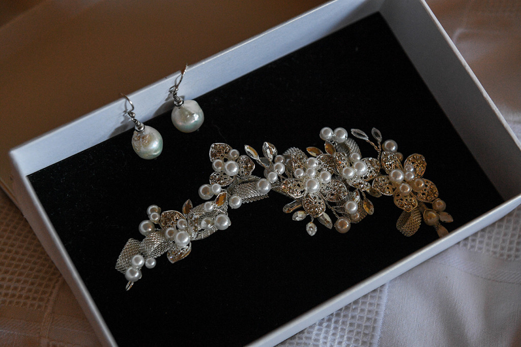 Closeup of pearl earrings and hair brooch of bride