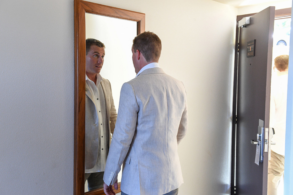 Reflection of groom in mirror at final checks during prep