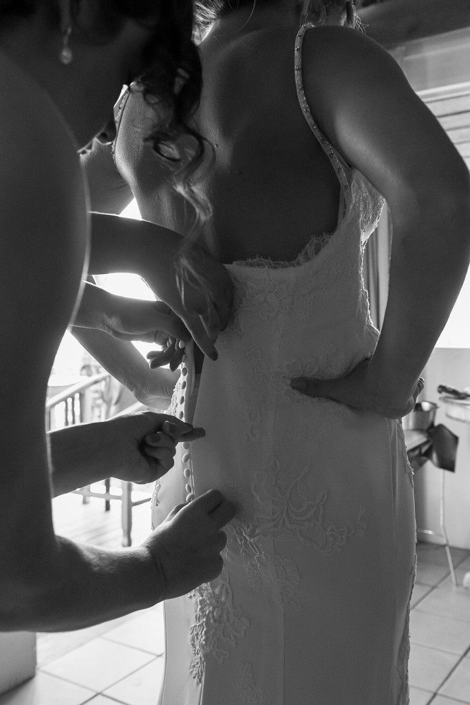 Black and white closeup of bride's dress being zipped