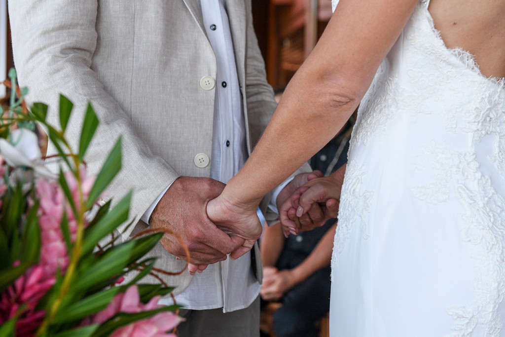 Closeup of bride and groom holding hands at the altar