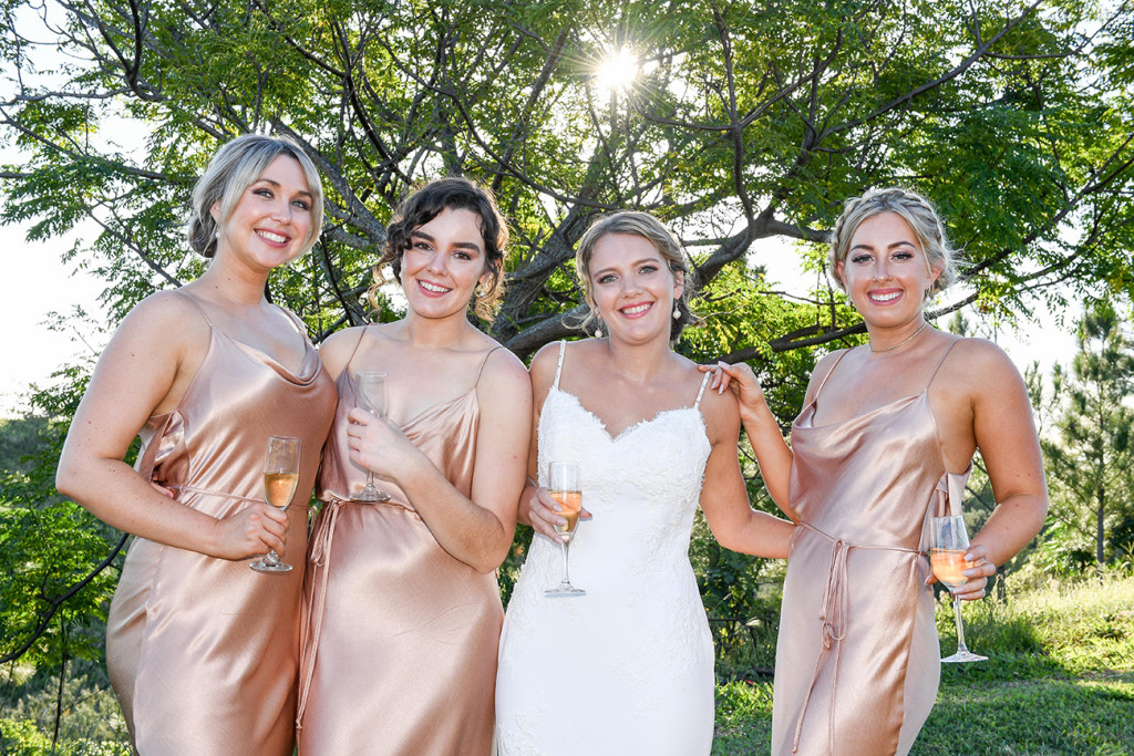 Bride poses with brides with glasses of champagne in Fiji countryside