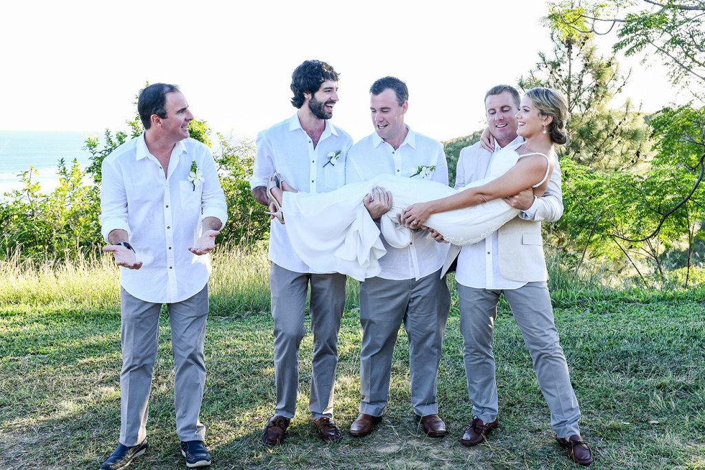 Groom and groomsmen toss bride against the sea in Fiji country