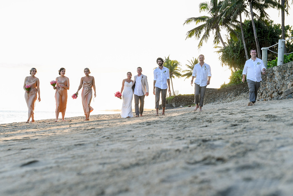Bridal party walks on the beach during sunset