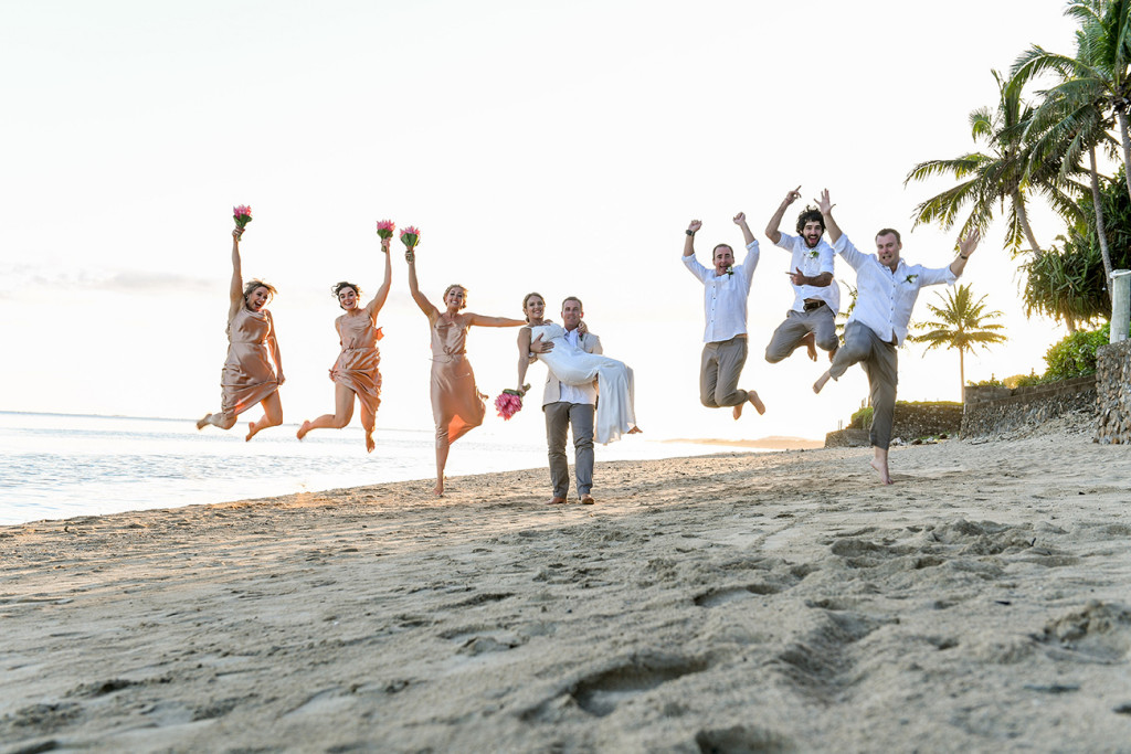 Bridal party jump against the sea and sunset in Fiji wedding