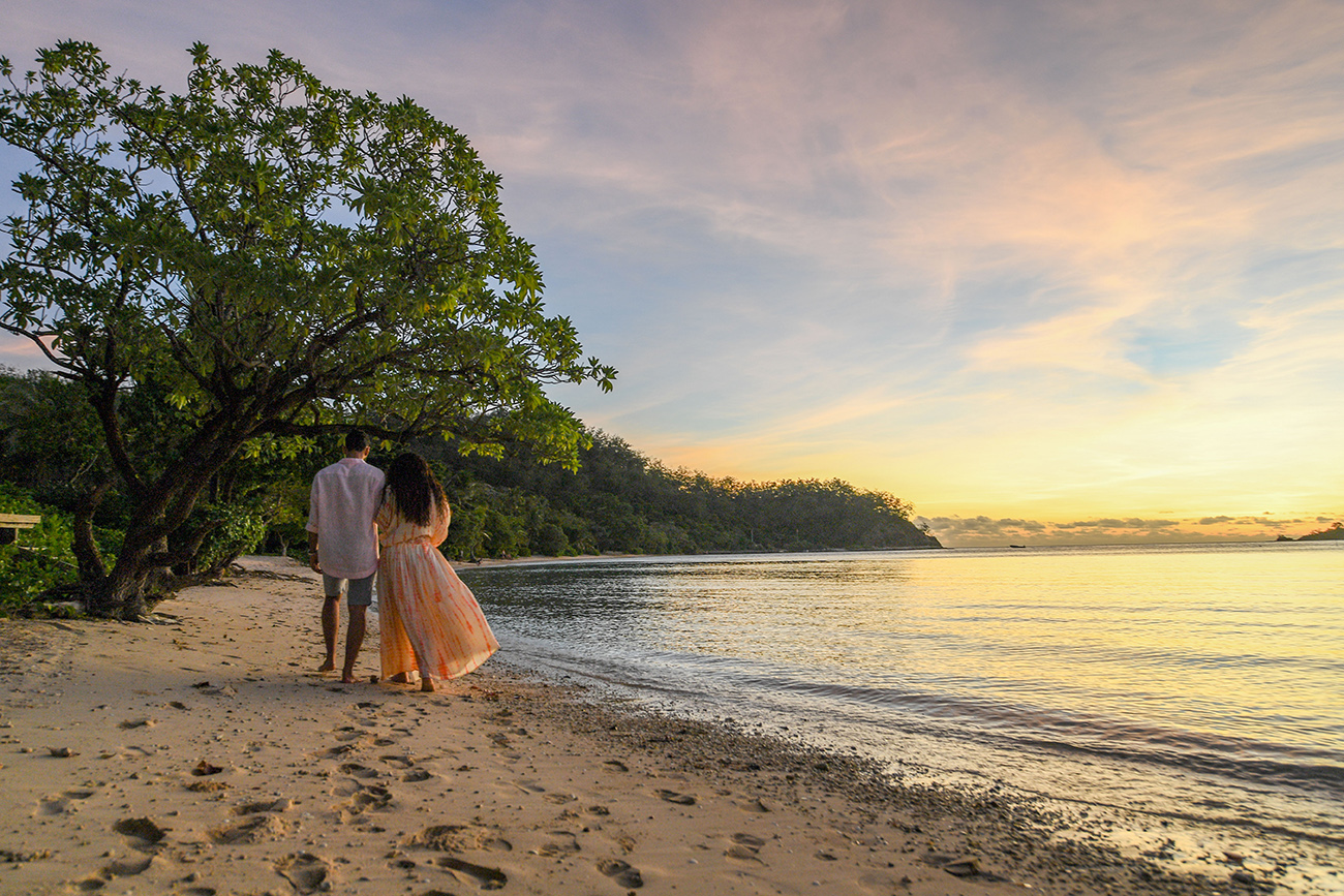 Newly wed walk along sea into the sunset in Likuliku Honeymoon