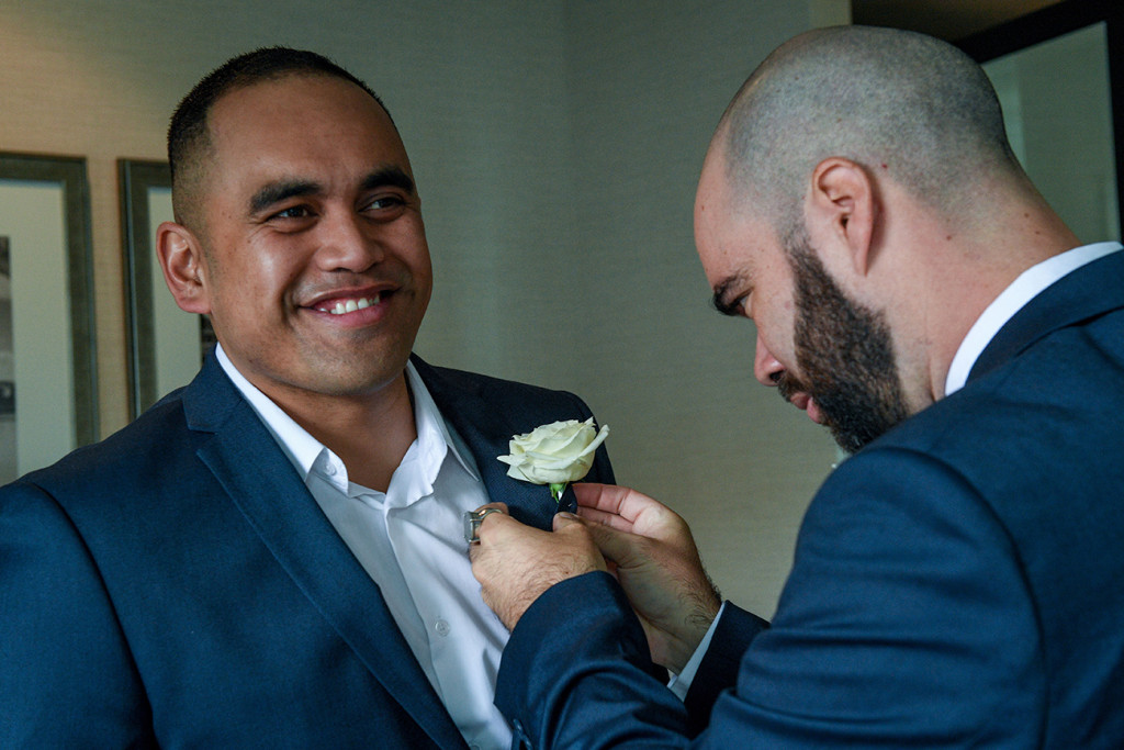 Groomsman helps groom adjust boutonniere