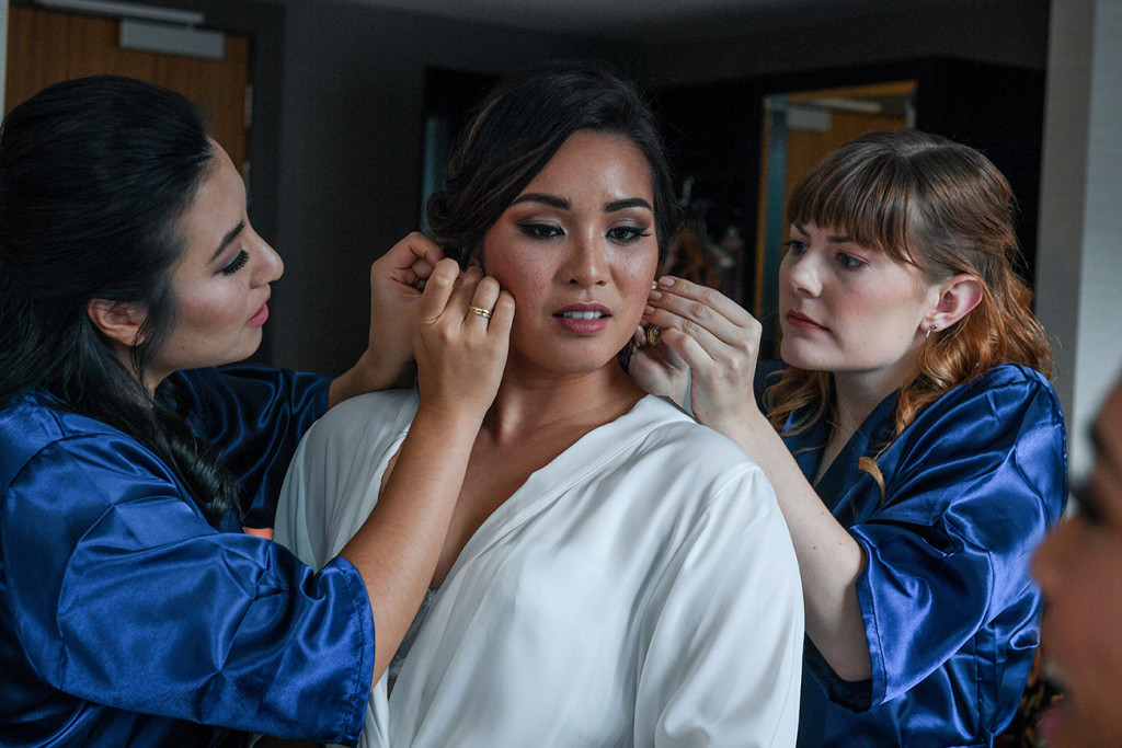 Bridesmaids fix the bride's earring during wedding preparations