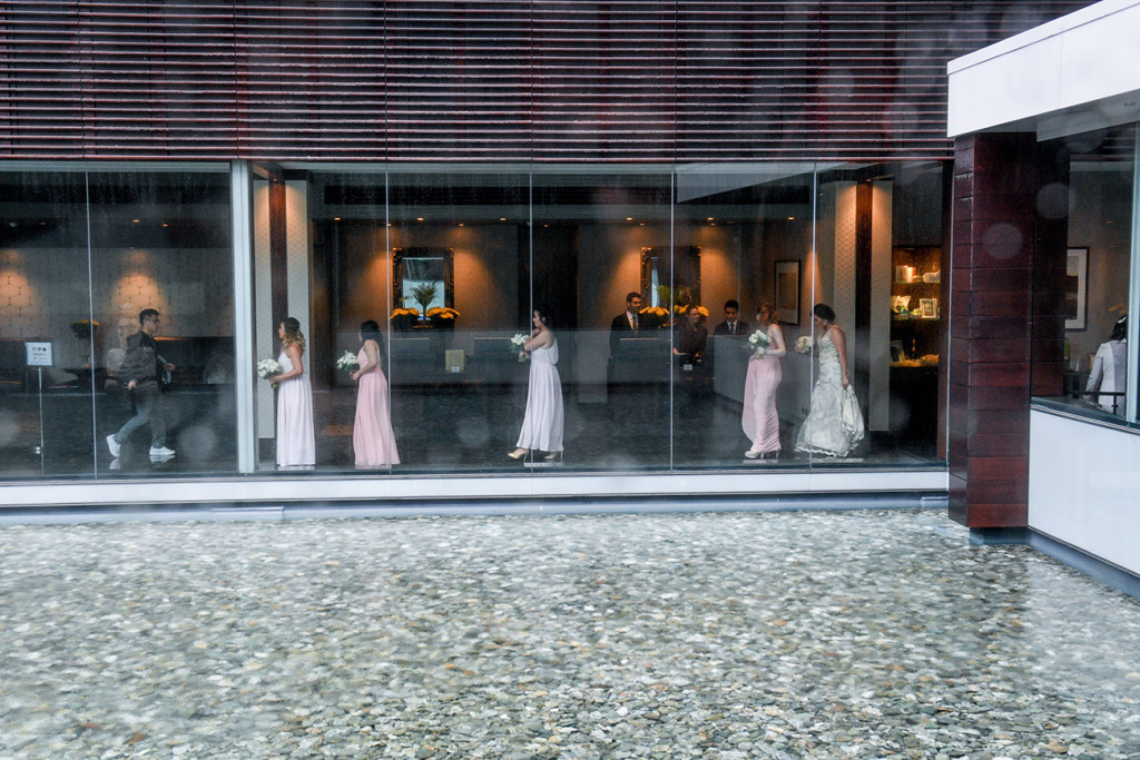 Bridesmaids walking towards ceremony venue through glass window