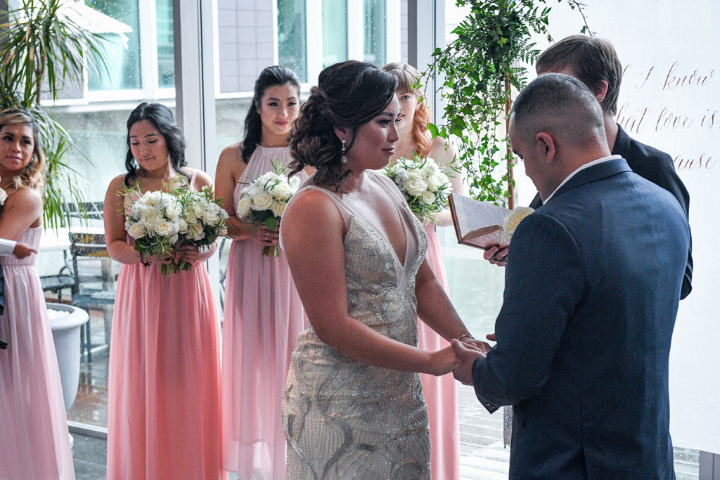 Bride and groom hold hands as they exchange vows at the altar