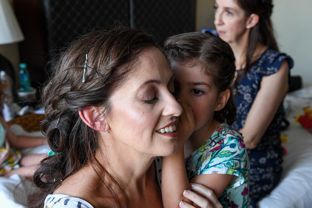 Daughter whispers to bride during preparation