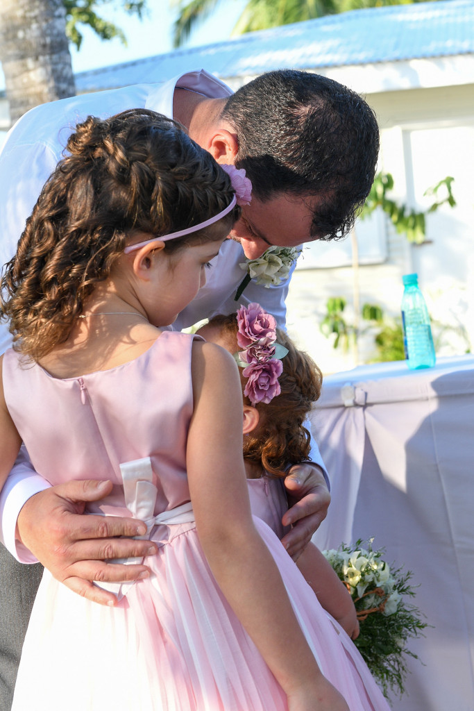 Flower girl whispers to her daddy in outdoor beach wedding Fiji