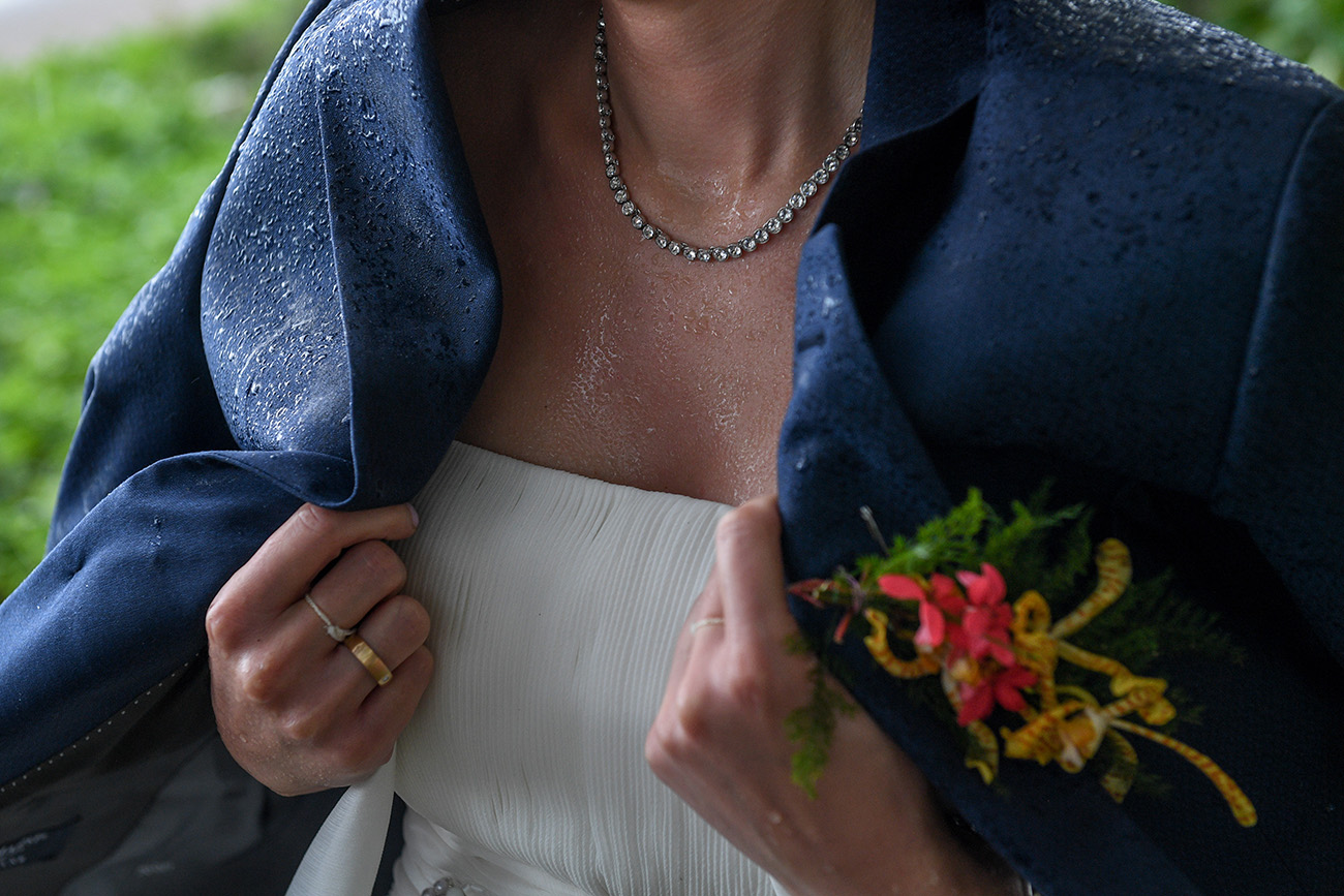 Closeup of shower droplets on grooms blazer as the bride covers herself