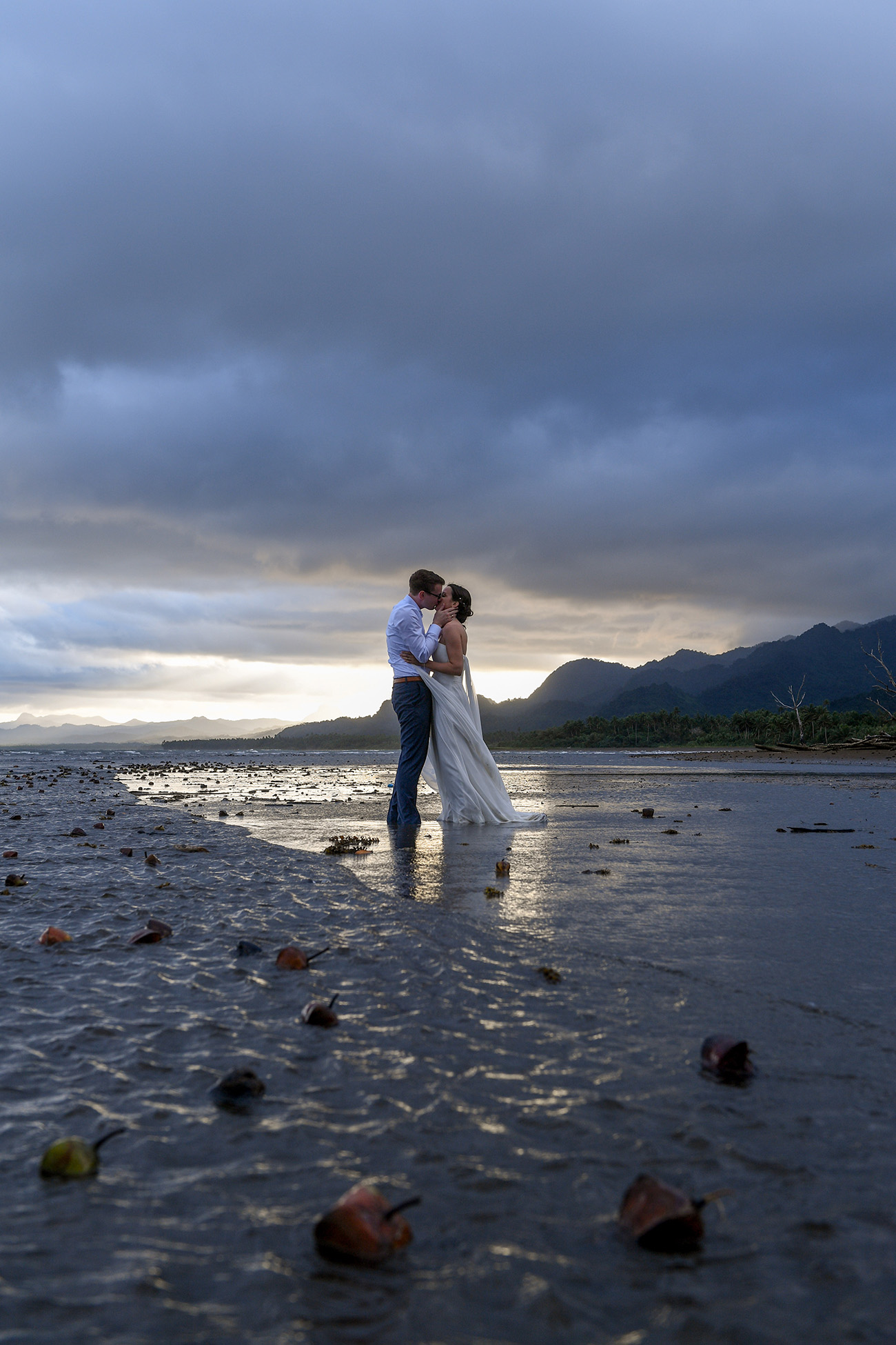 Couple kiss against stormy gray cloud while standing in the sea