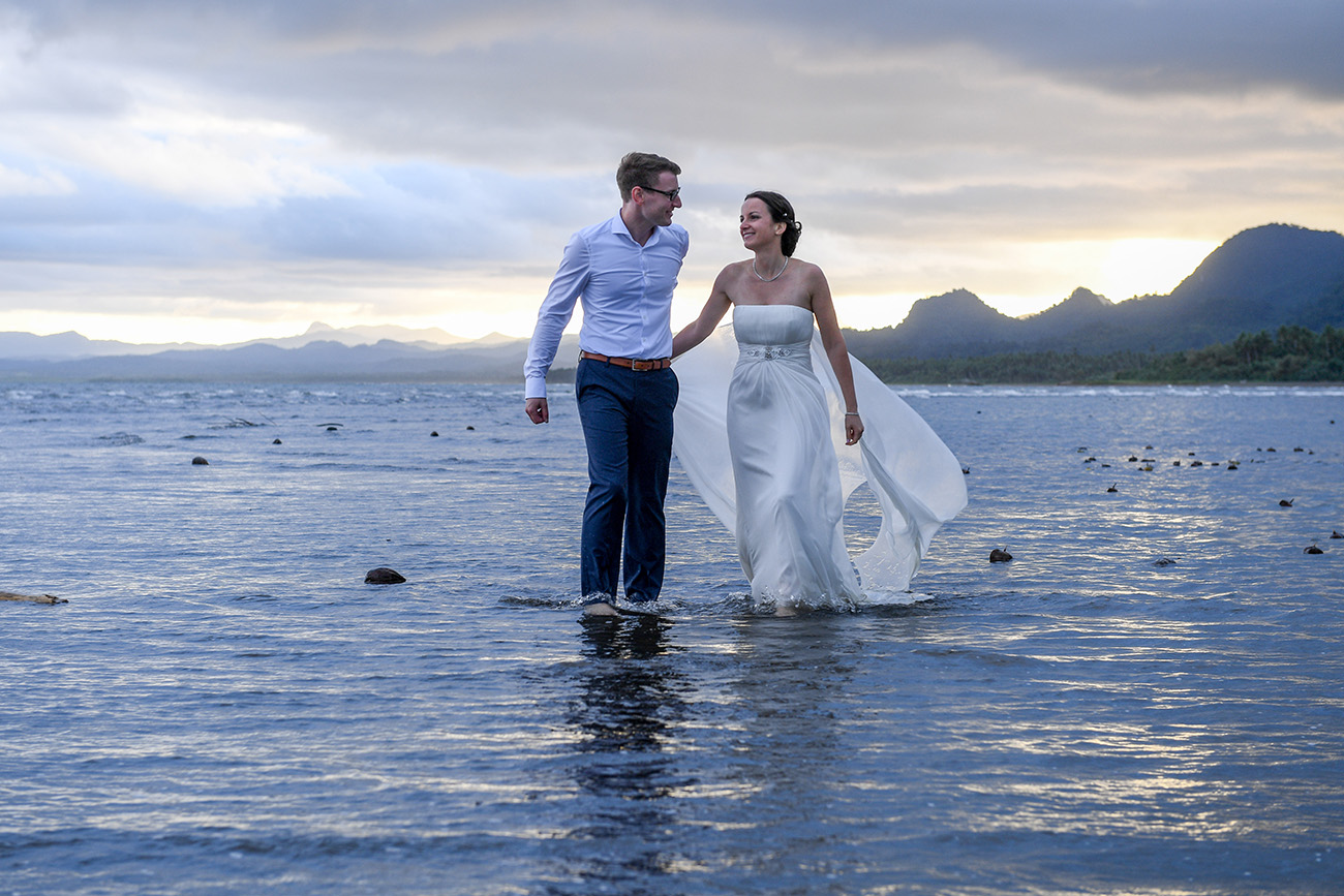 The bride and groom stare longingly at each other as they stand in the Pacific Ocean