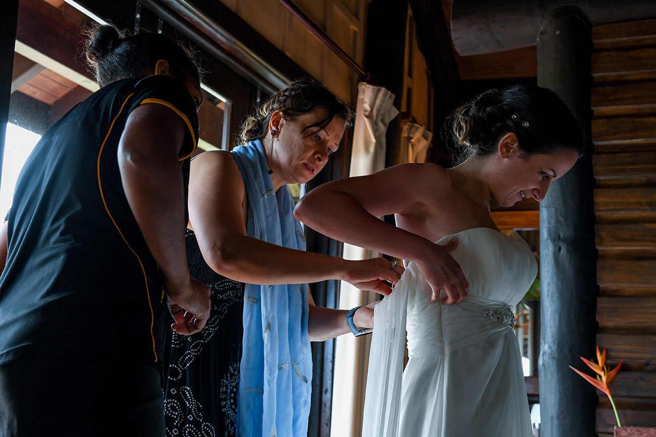 The bride's sister helps her fasten her dress