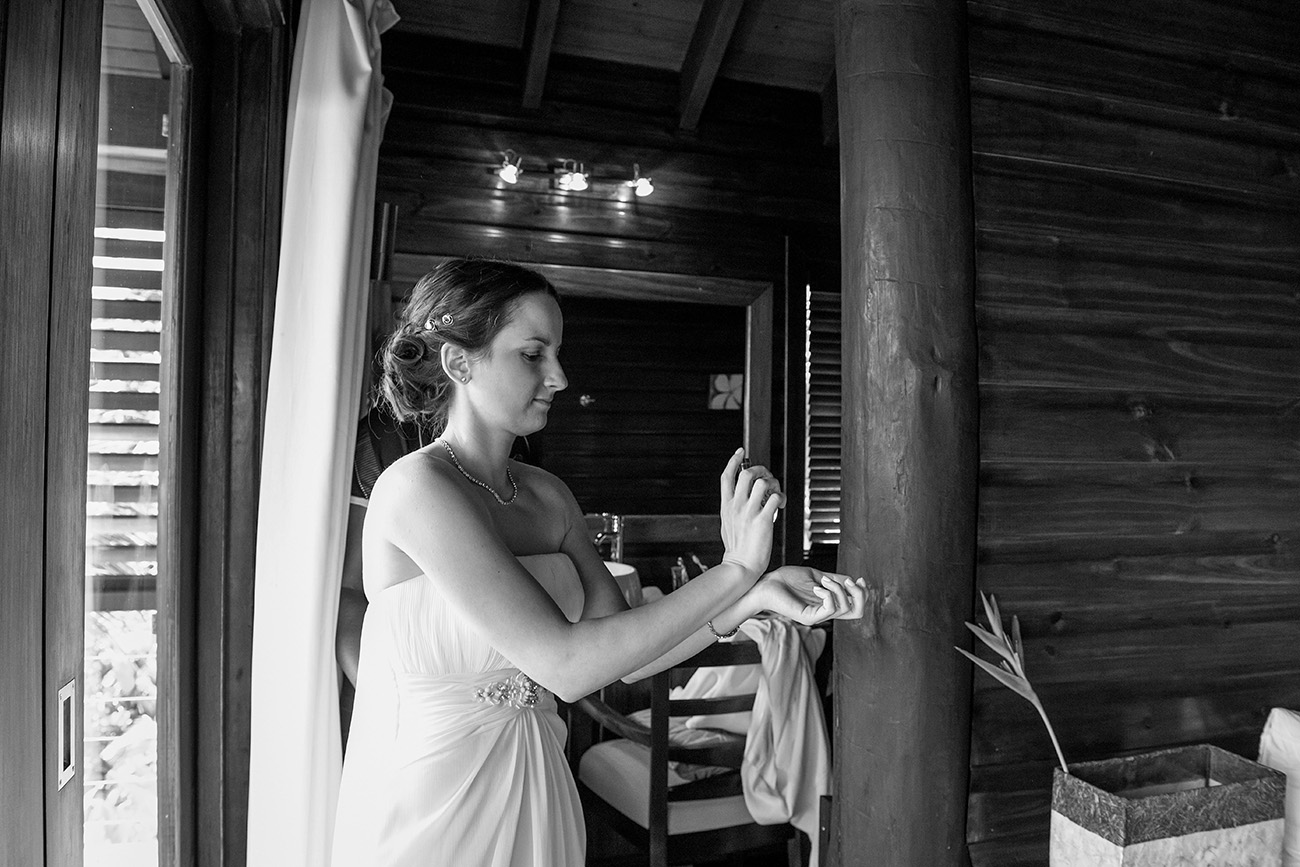 Black and white photo of the bride rubbing perfume onto her wrists at her wedding