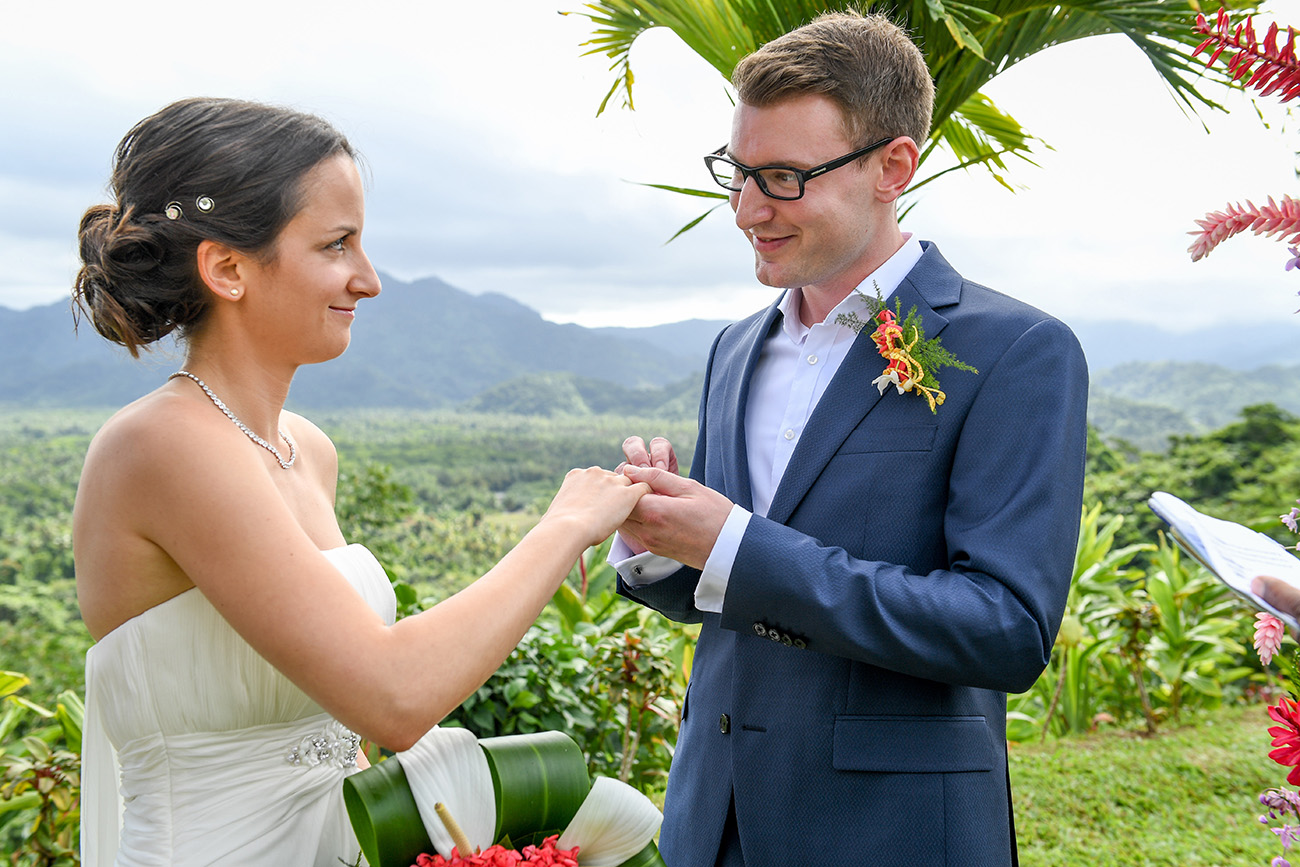 Groom smiles as he puts ring on his bride in Fiji island countryside wedding